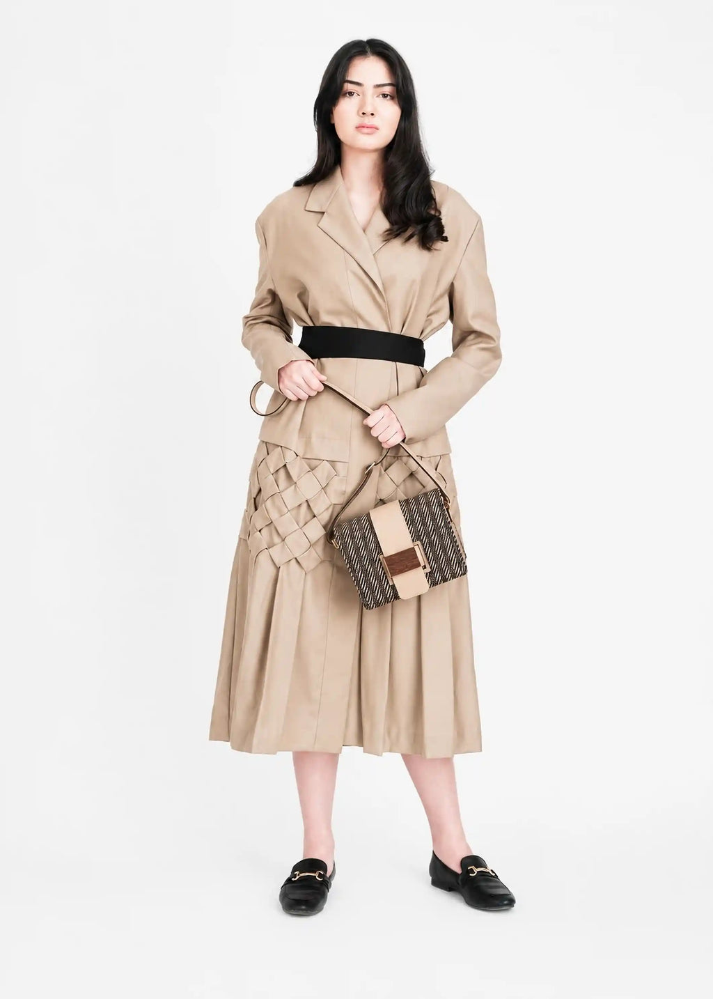 Model carrying Berlin Twist Dusk crossbody bag in beige — worn at hip level