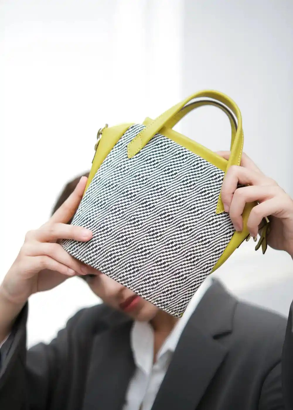 Woman wearing Chicago Mini Rise Salt & Pepper handwoven bag with yellow leather