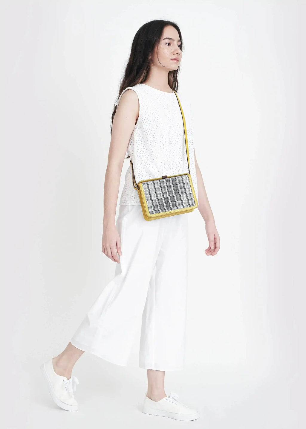 Woman wearing Zürich Rise Salt & Pepper crossbody bag with yellow nappa leather over shoulder