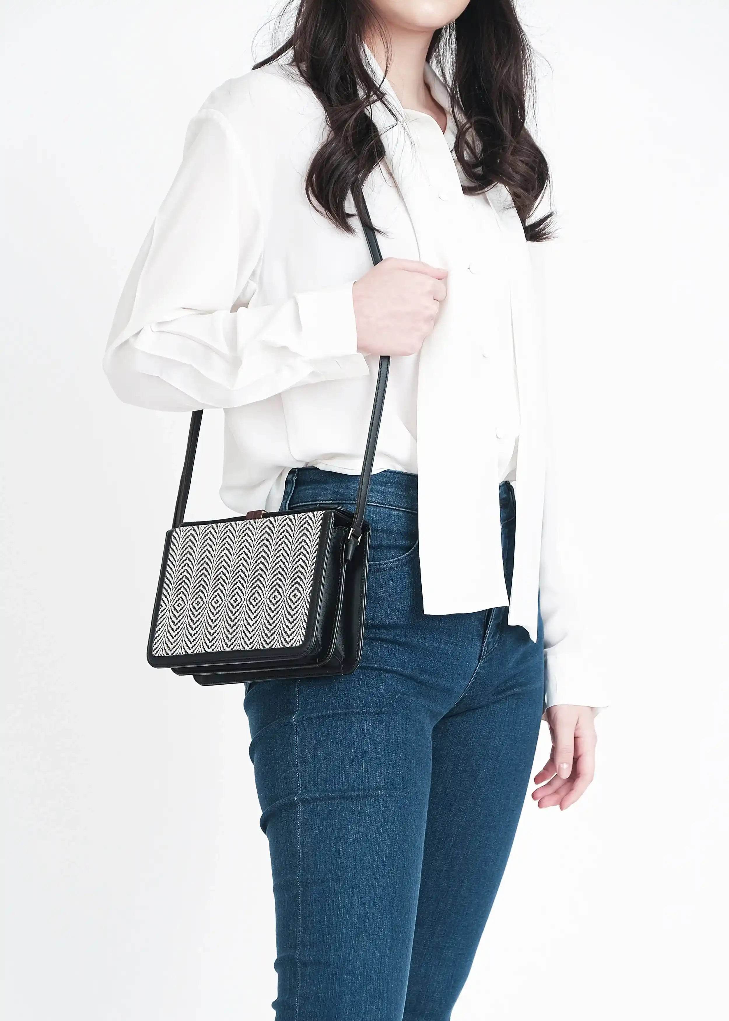 Model holding Zürich Sizzle Salt & Pepper crossbody bag showing full structured body